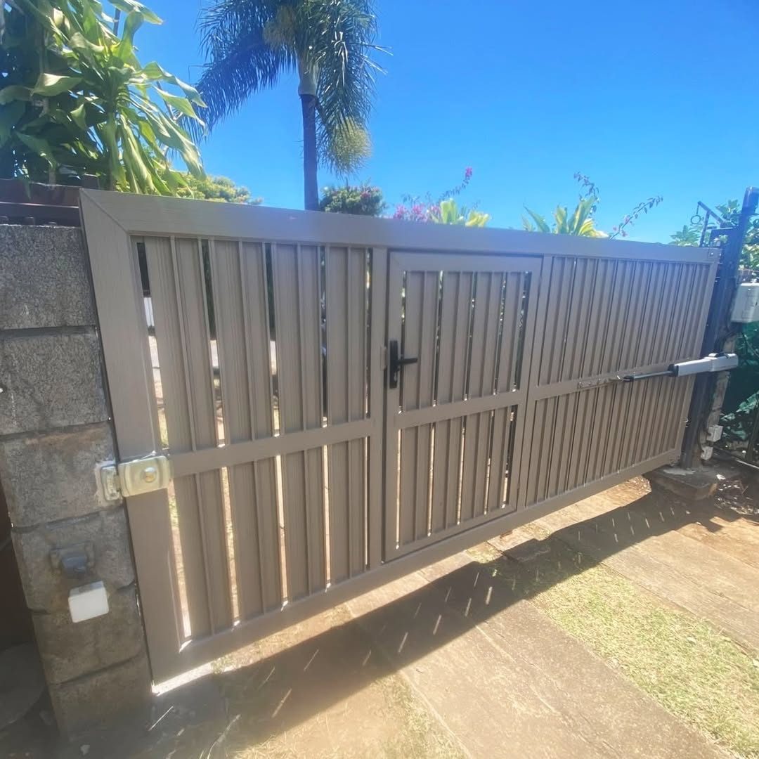 Portail battant en aluminium taupe à lames verticales, avec motorisation à bras